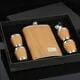 Wooden hip flask set with funnel and stainless steel cups, elegantly presented in a stylish black box.