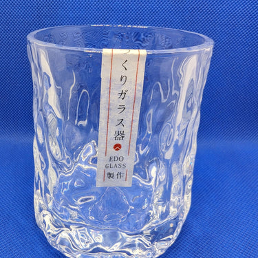 Japanese style hammer crystal whisky glass with thick, heavy design on a blue background