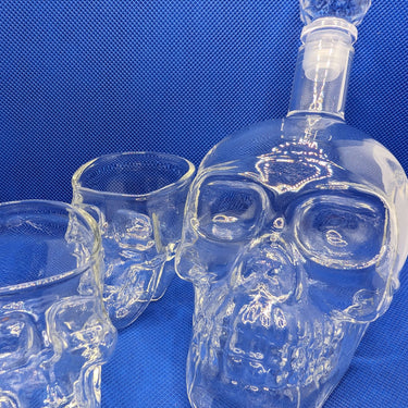 Skull whisky crystal bottle and glasses set on blue background for edgy, elegant drinking experience.