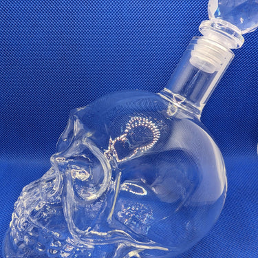 Crystal skull whisky bottle with diamond-shaped stopper on blue background, showcasing edgy and elegant design for whiskey enthusiasts.