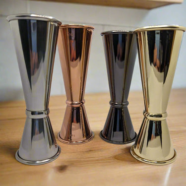 Stainless steel, copper, dark, and gold cocktail jiggers for precise mixology in a stylish bar setup.