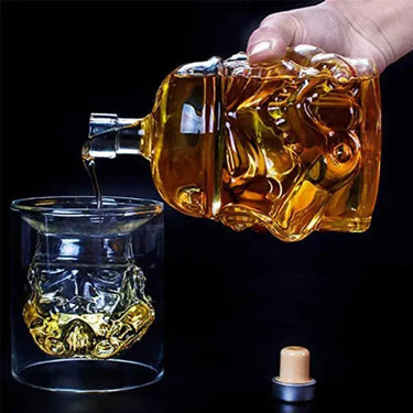 Hand pouring whiskey from a skull-shaped decanter into a glass, showcasing a unique and artistic drink presentation.