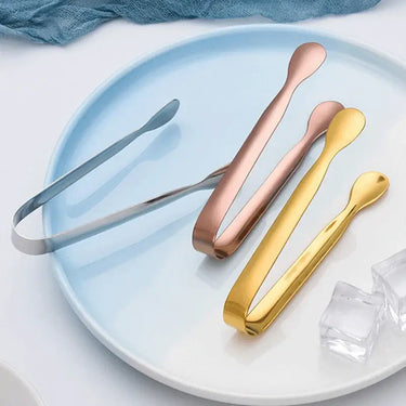 Set of stainless steel ice cube tongs in silver, rose gold, and gold on a blue plate, perfect for elegant drink service.