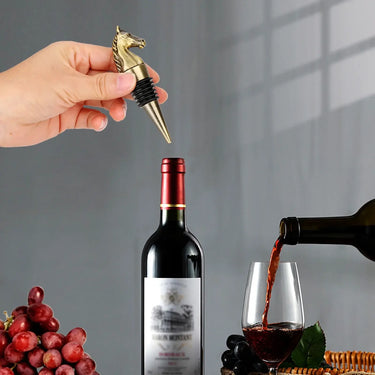 Elegant vintage horse head wine stopper next to wine bottle and grapes, showcasing timeless sophistication and design.