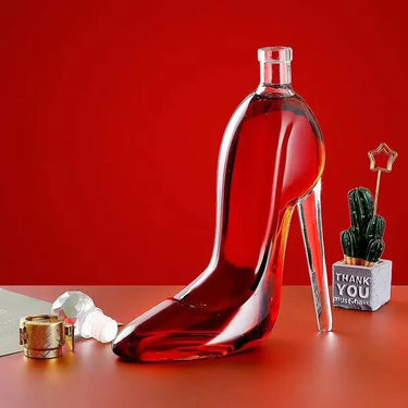 High-heeled shoe decanter in red glass, elegantly designed for whiskey presentation on a stylish tabletop setting.