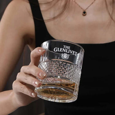 Woman holding a Glenlivet Collection Whisky lead-free glass with whisky, showcasing luxury and refinement.