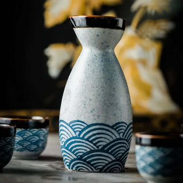 Japanese Waves Sake Set Ceramic decanter and cups with ocean wave design on a table.