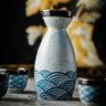 Japanese Waves Sake Set Ceramic decanter and cups with ocean wave design on a table.