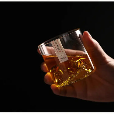 Hand holding a Japan 3D Mountain Whisky Glass filled with whisky, showcasing intricate 3D mountain design against a dark background.