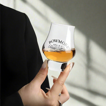 Close-up of Bowmore Single Malt Scotch Whisky in a sniffer glass held by a hand, showcasing elegance and sophistication.