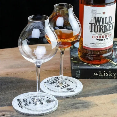 Two British Blender's Scotch Whisky Tasting Glasses on coasters, with a bottle of Wild Turkey Bourbon Whiskey in the background.