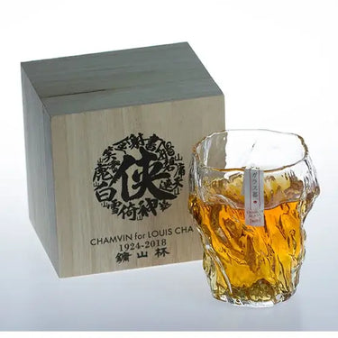 Unique whiskey glass with an artistic design alongside a wooden gift box, showcasing creativity and craftsmanship.