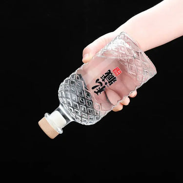 Hand holding a 500ml wooden stopper lead-free whisky decanter with Japanese characters, against a black background.