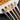 Stainless steel long handle mixing spoons in various finishes arranged beside a plate.