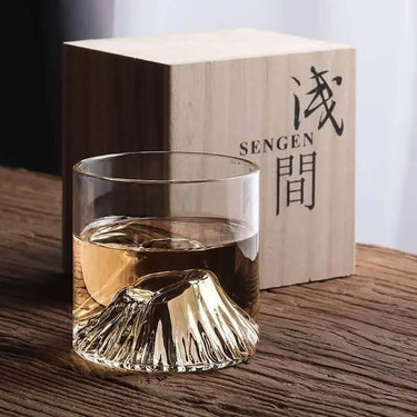 EDO Fuji whisky glass with Mount Fuji design by Liu Siyu, beside Sengen-branded wooden box on a wooden table.