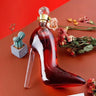 High-heeled shoe decanter in red glass, elegantly designed for whiskey presentation with decorative flowers and a small plant.