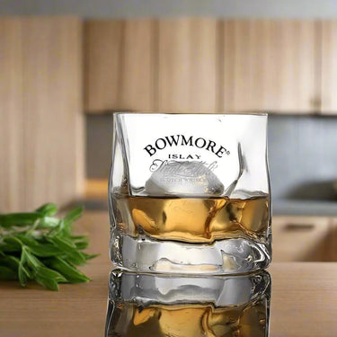 Bowmore Single Malt Scotch Whisky in a crystal glass on a wooden countertop.