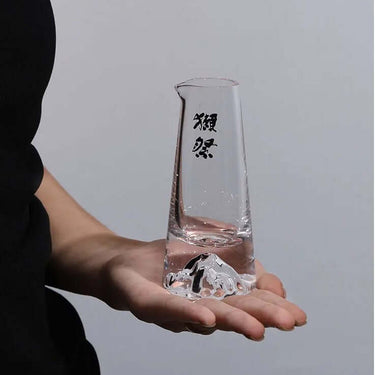 Hand holding a crystal carafe from the Dassai Japanese Traditional Handcrafted Crystal Sake Set for cold sake